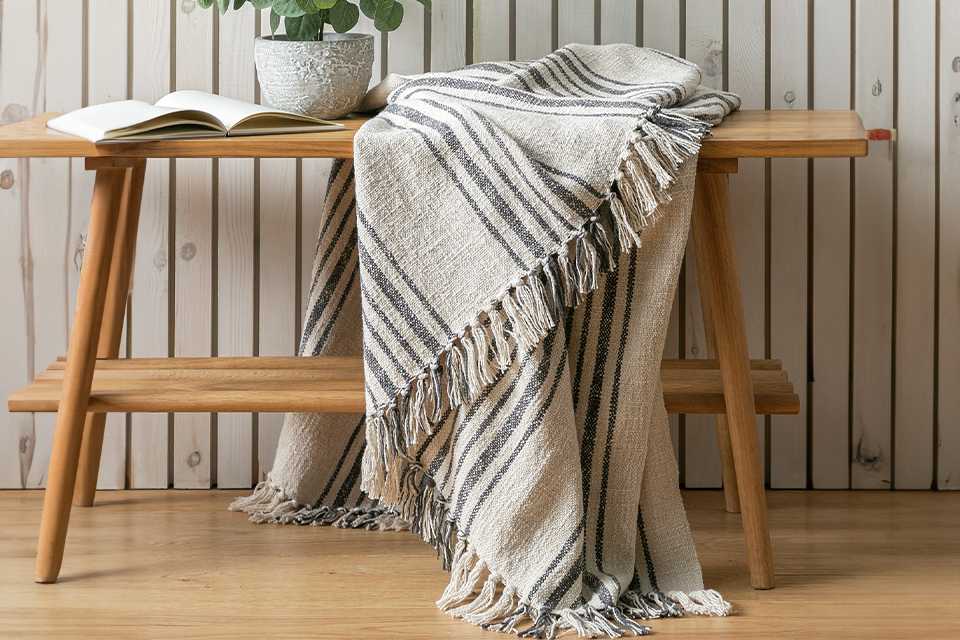 Habitat yarn dye stripe throw in natural finish draped over a wooden bench.