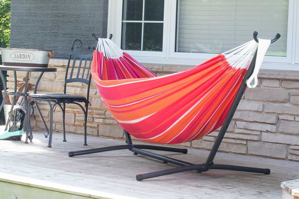 A Vivere Mimosa Double Hammock with Metal on a patio.