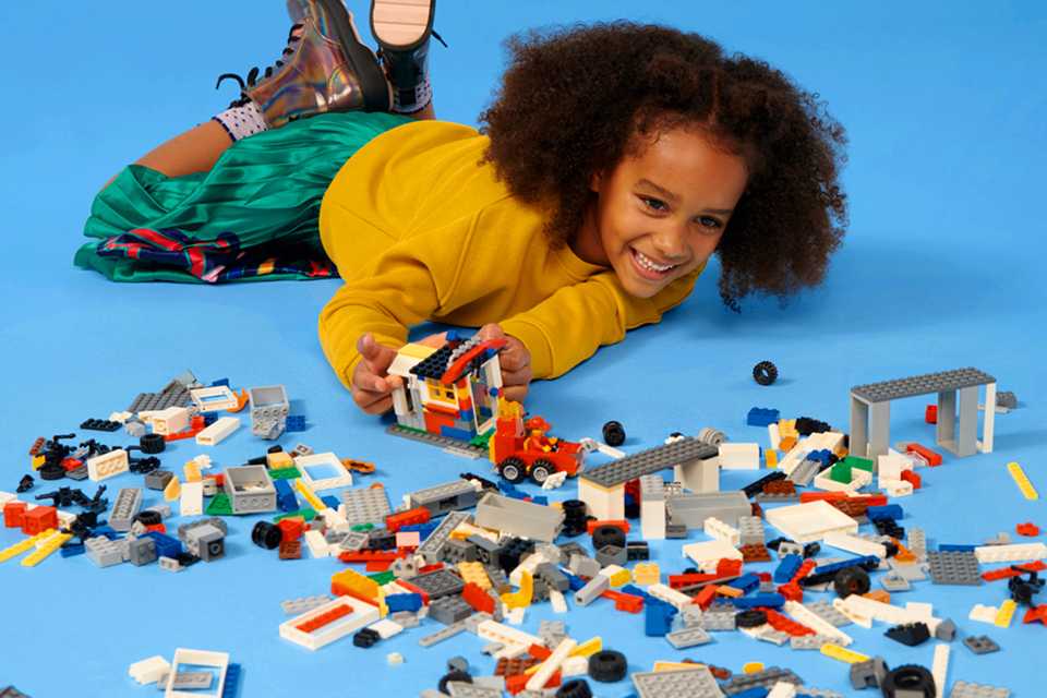 Child playing with LEGO® bricks on a blue background, showcasing creativity and building skills.