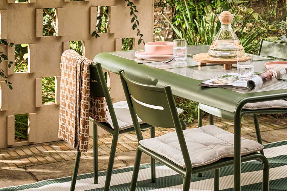 A green garden table and chair set laid out beautifully for a meal.