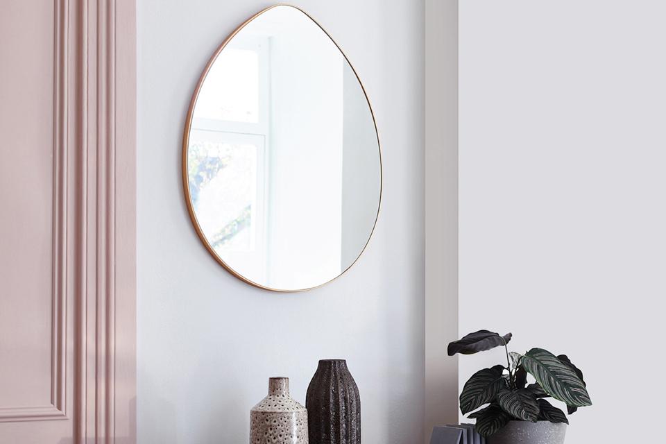 Teardrop gold mirror on pink wall.