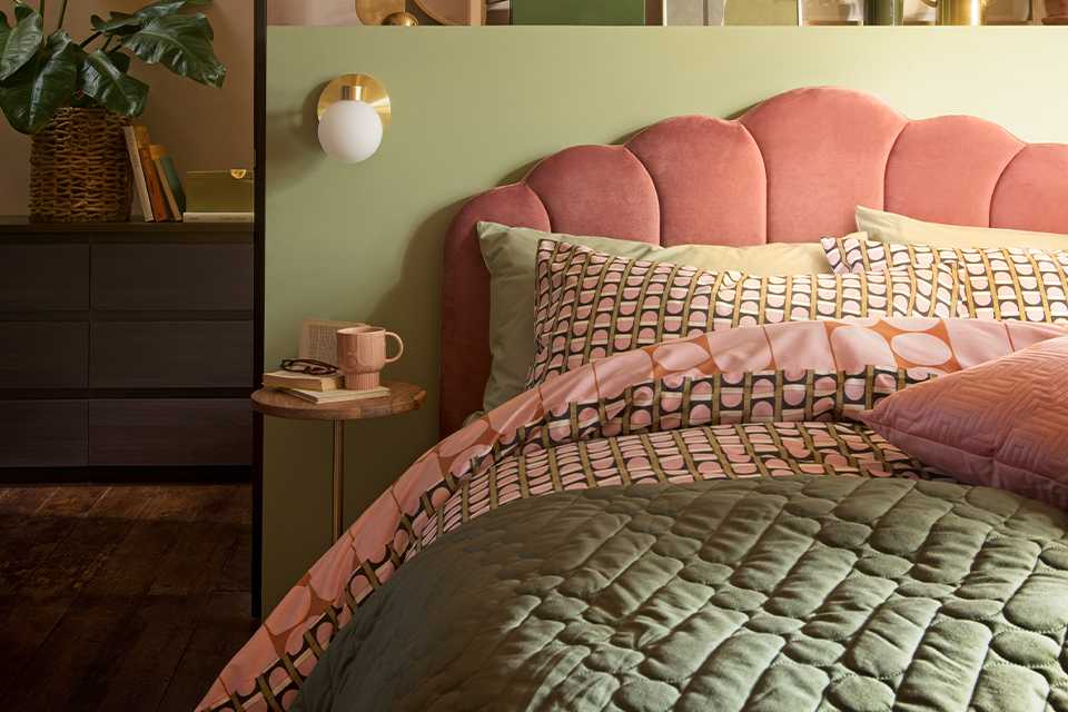 Pink velvet headboard and green and pink bedding on bed