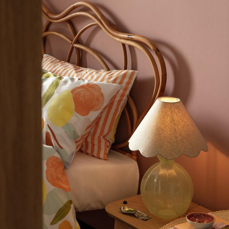 A glass table lamp on an oak bedside table.