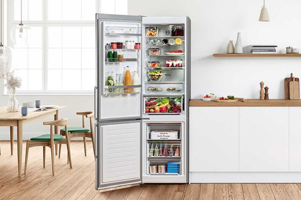 A Bosch silver freestanding fridge freezer stocked with food and drinks in a dining room setup.