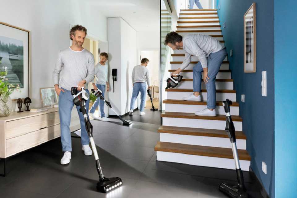 A man cleaning all the corners of his house with a Bosch Unlimited 6 cordless vacuum cleaner.