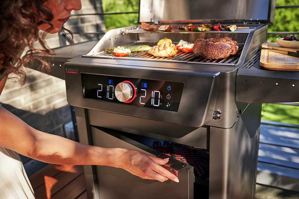 A woman using a Char-Broil Evolve Electric BBQ placed outdoors on a patio.