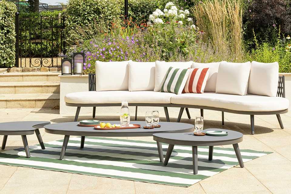 Habitat Santorini 6 Seater Rattan Effect Garden Sofa Set placed outdoors with cushions on it.
