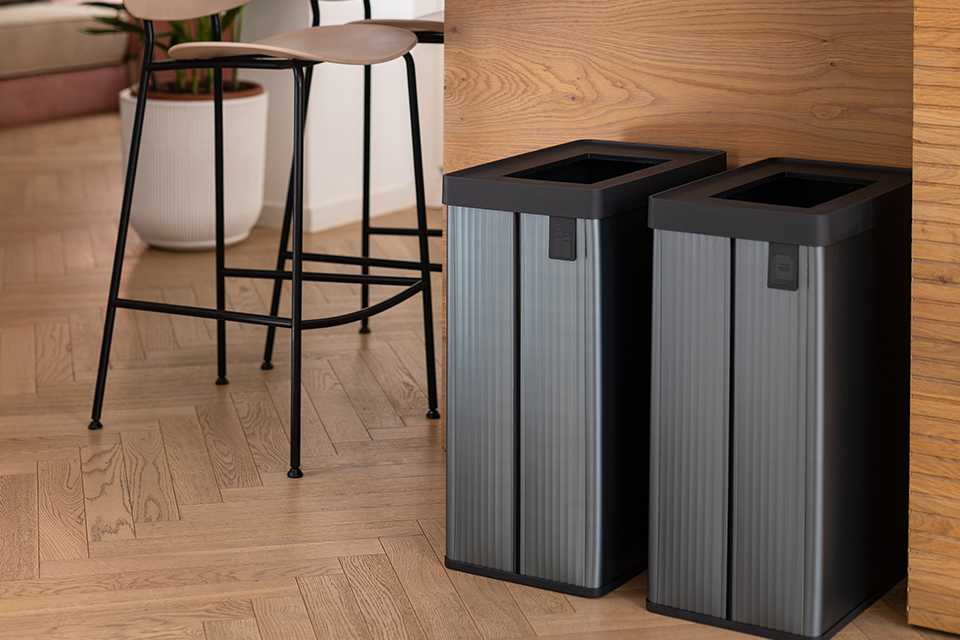 Two grey coloured Curver Verto recycling bin placed under a dining table.