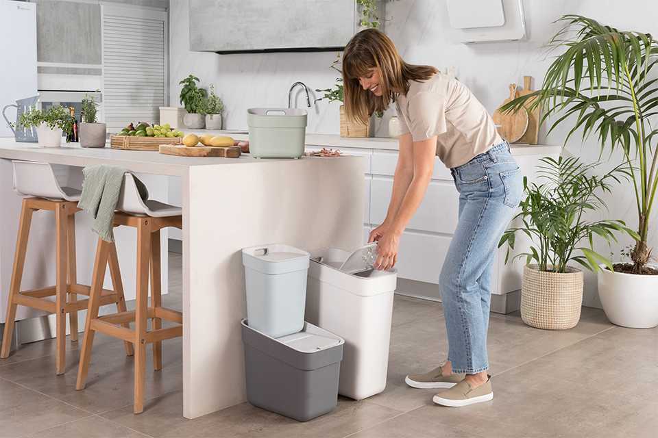 A woman opening a Curver recycling kitchen bin.