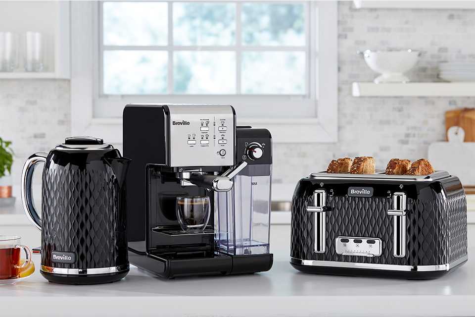 A black set of Breville toaster, coffee machine and kettle placed on a white kitchen countertop.