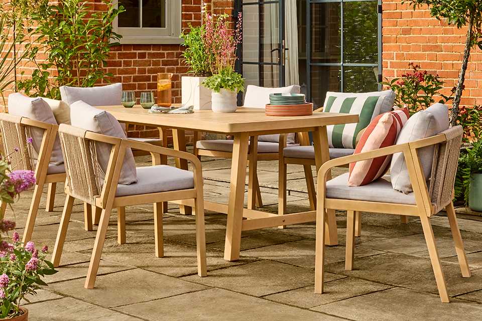 A Habitat Hania 6 seater wooden patio set in natural finish placed outdoors.