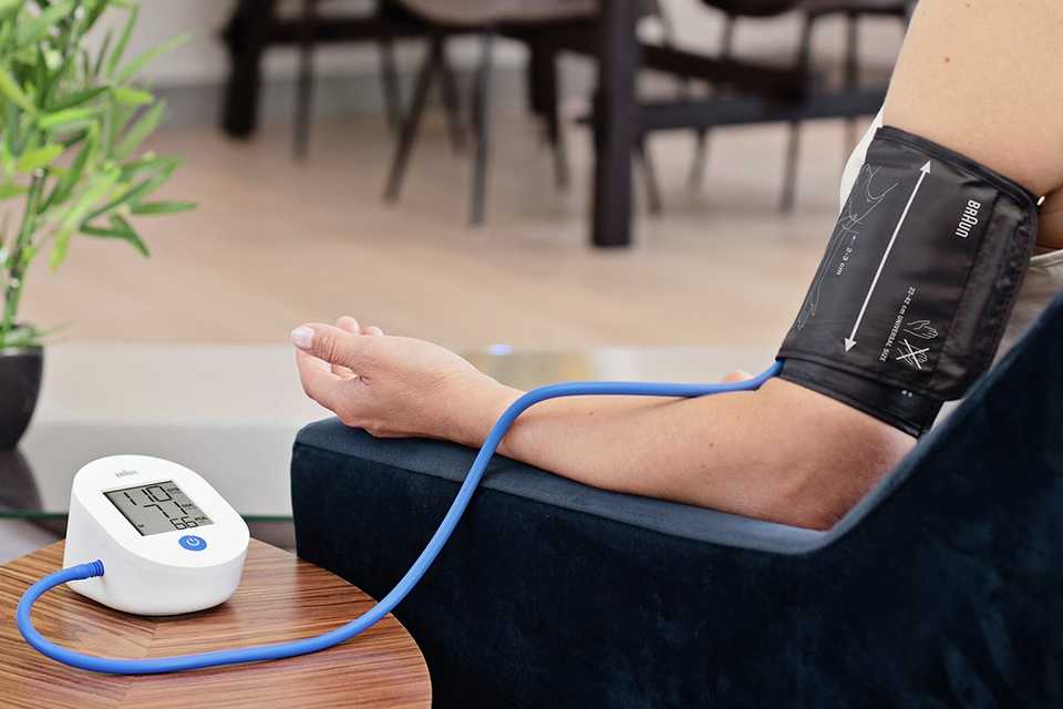 A Braun ExactFit 1E Upper Arm Blood Pressure Monitor being used to measure a person's BP.