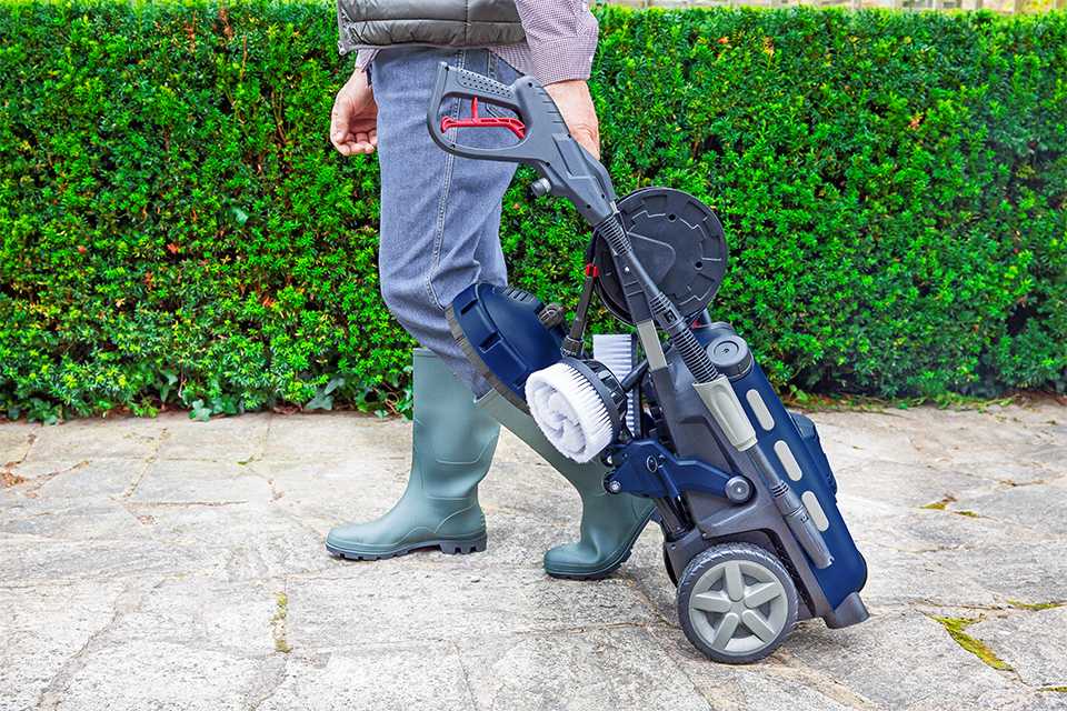 A man moving the Spear & Jackson pressure washer - 2000W on its wheels.