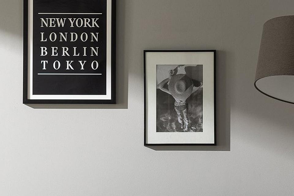 One frame hanging above another on a grey wall.