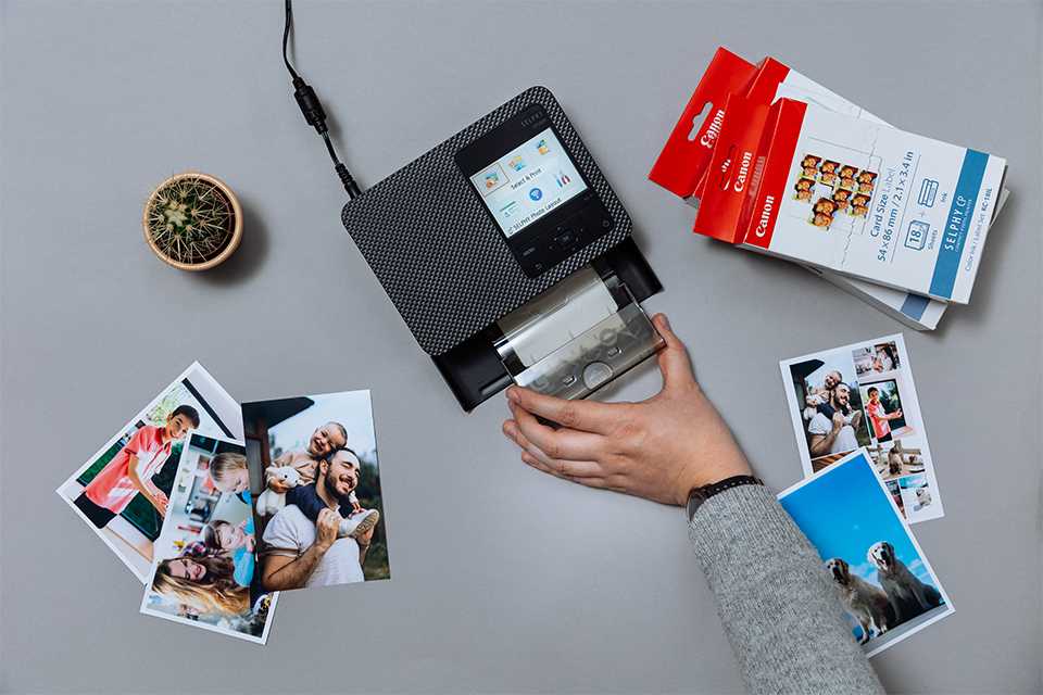 A person printing photographs using Canon SELPHY CP1500 printer.