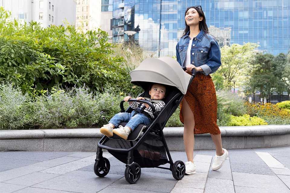 A woman pushing a baby in a Graco Myavo Quick-Folding Travel Stroller - Midnight.