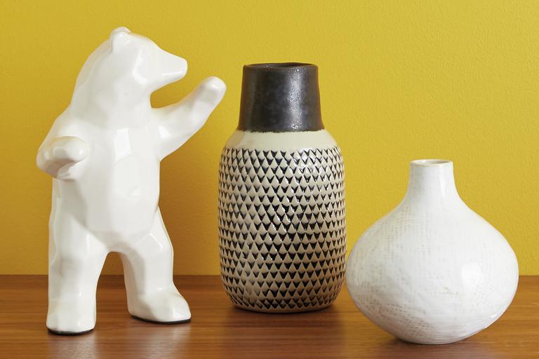 Two vases and an animal figurine against a mustard yellow background.