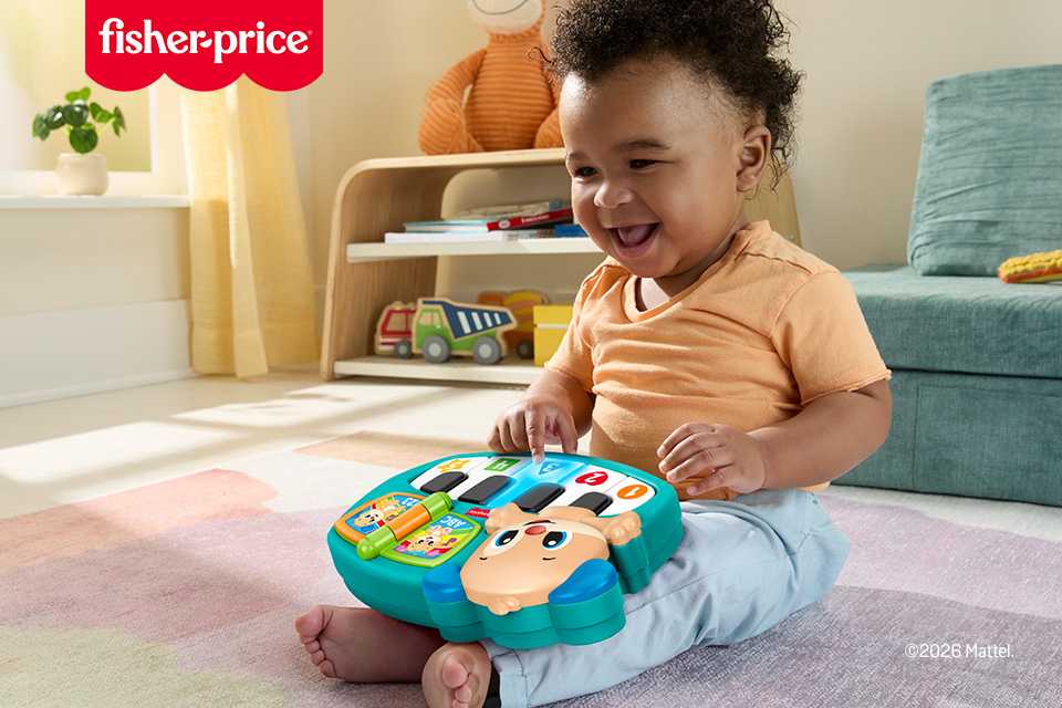 A happy baby playing with a Fisher-Price Puppy Piano.