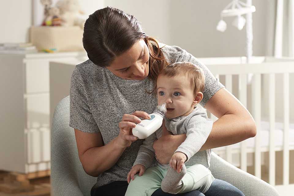 A mother using a nasal aspirator to clean her baby's nose.