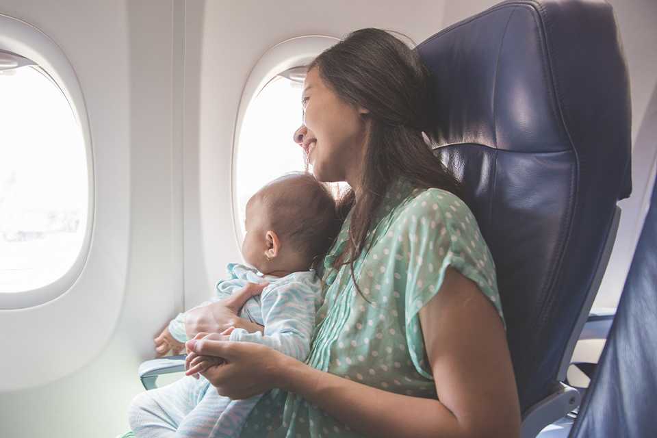 A mother and a baby sitting together in an airplane.