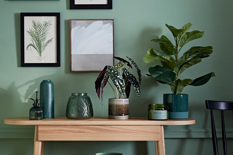 Console table with green bases and leaf prints above it.