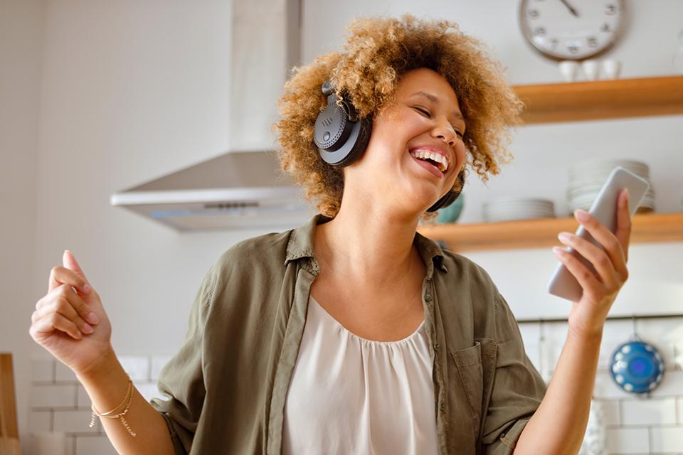 A woman wearing headphones looks at a mobile phone.