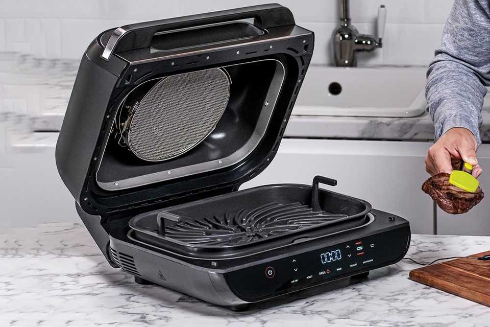 A man using a Ninja Foodi MAX Health Grill Air Fryer & Dehydrator.