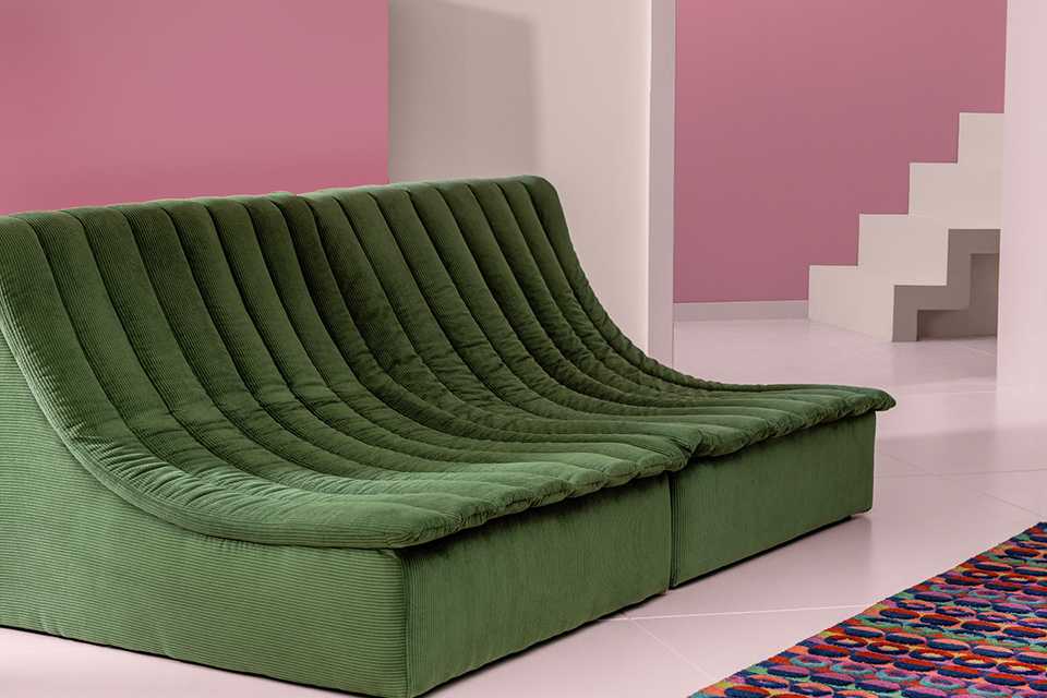 A Habitat scoop chair in green next to a colourful rug.
