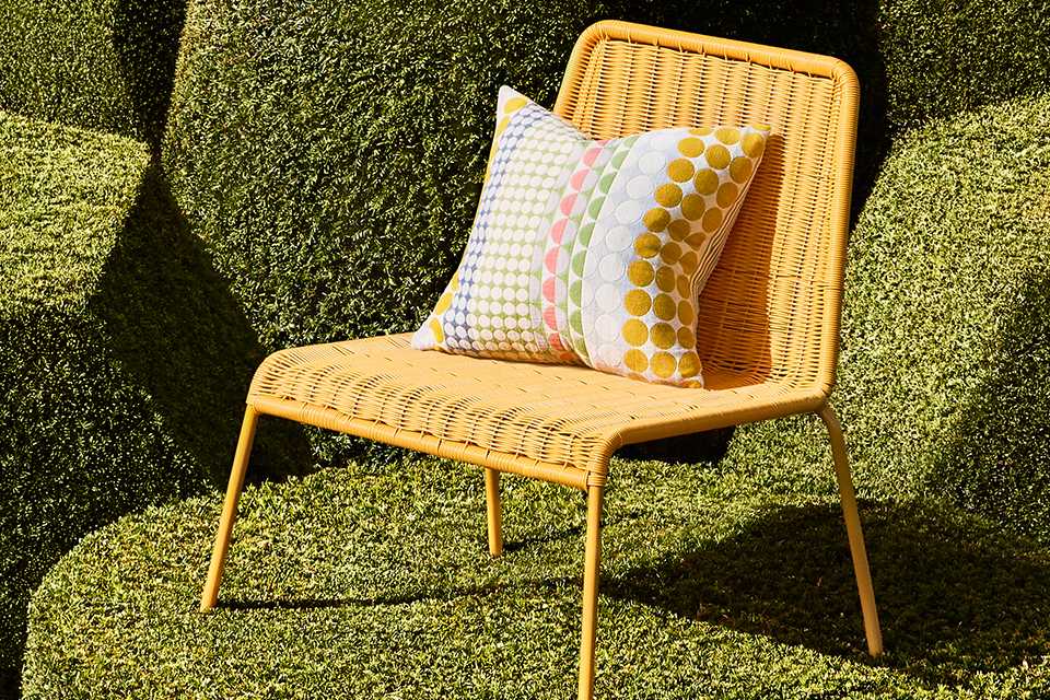 A yellow Habitat garden chair with a cushion on it.