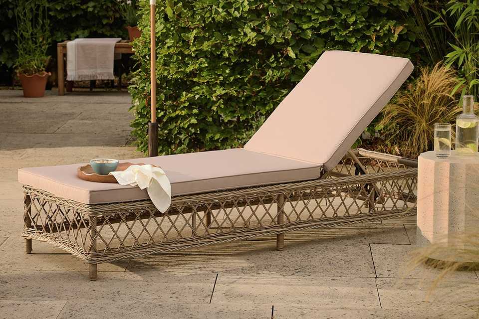 garden sun lounger with cream cushion in garden