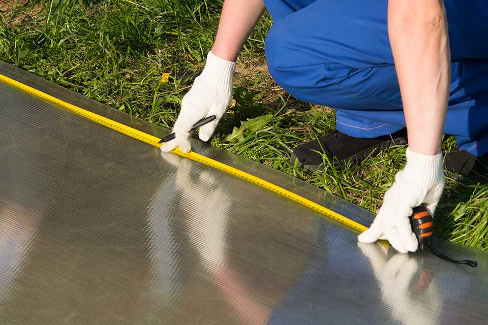 A person taking measurements for installing a greenhouse.