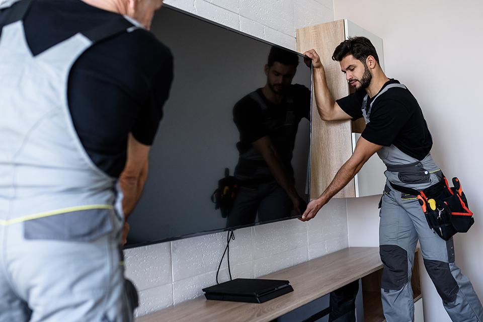 Two men wall mounting a TV in a living room.