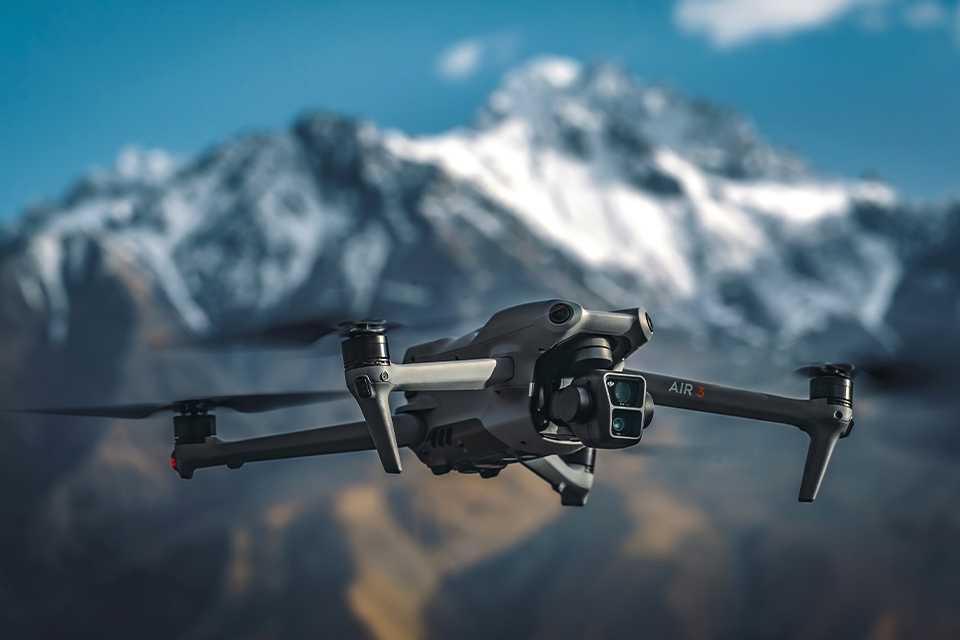A DJI Air 3 camera drone flying in the mountains.