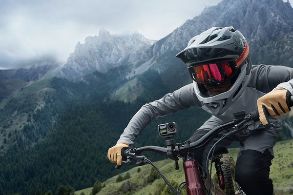 A person riding a mountain bike with DJI Osmo Action 4 camcorder attached to the handlebar.