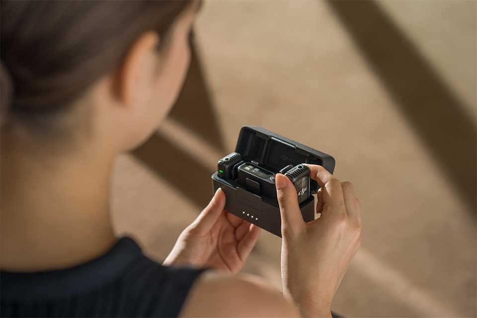 A woman in black top taking the DJI Mic 2 audio recorder out of the box.