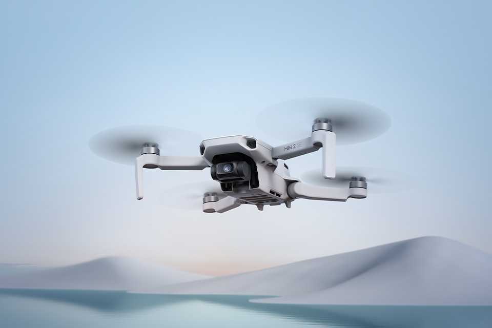 A DJI Mini 2 SE camera drone flying over water.
