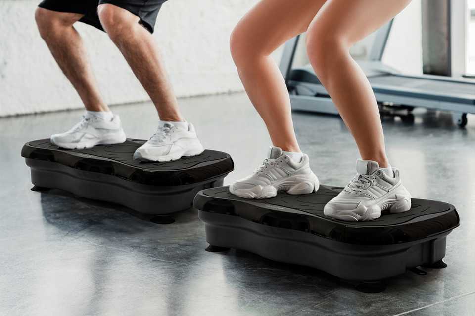 closeup image of two people using vibration plates in a gym setting