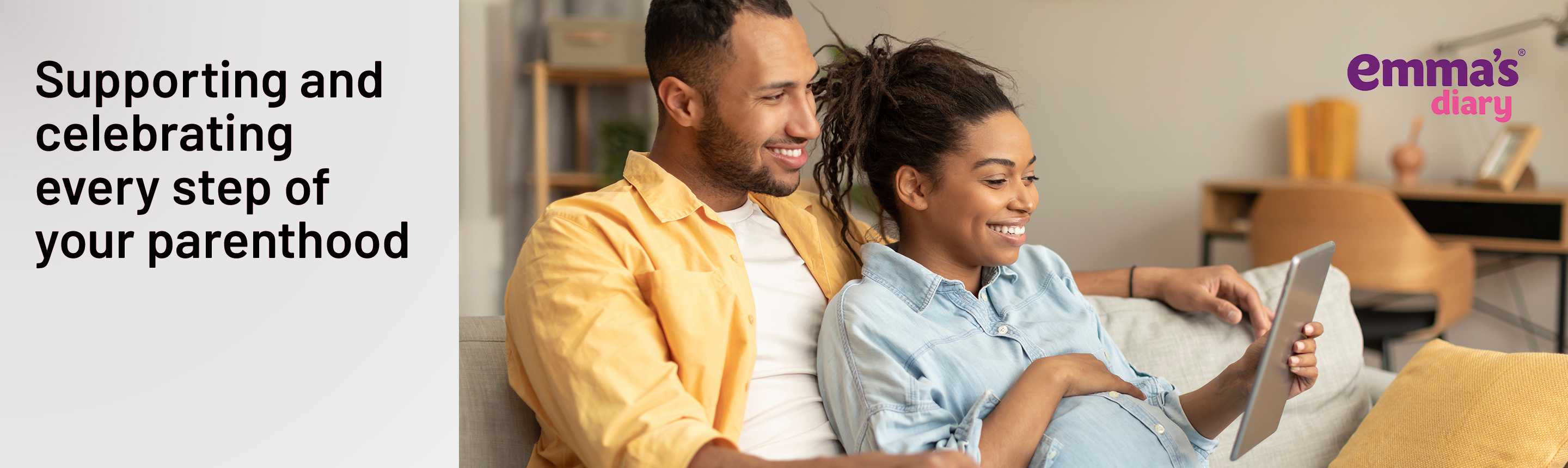 A pregnant couple looking at a tablet for baby related information.