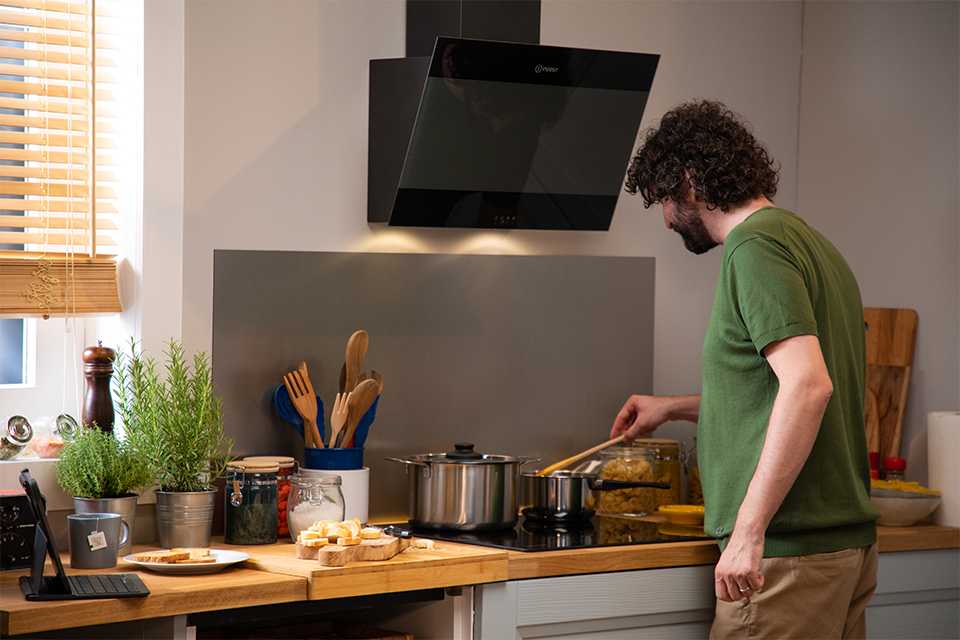 A man using an Indesit electric induction hob to cook food in the kitchen.