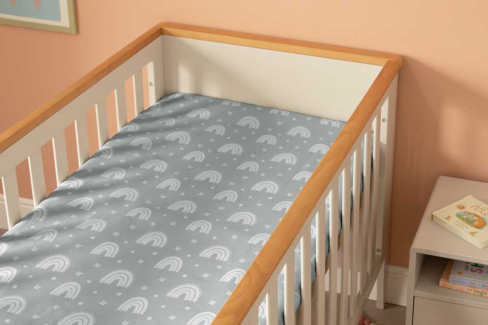 A Habitat rainbow themed grey fitted sheet on a cror mattress.