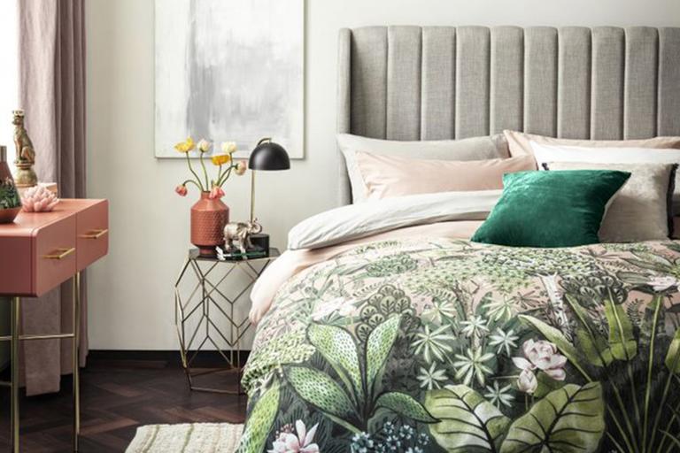 Green floral bedding on grey velvet bed.