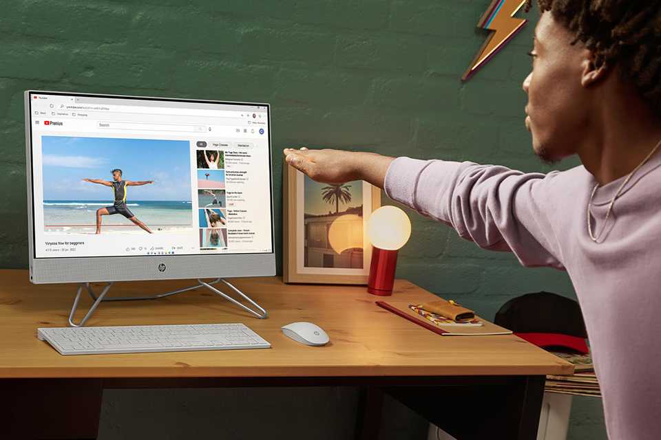 A boy doing a yoga pose whilst watching a video on HP All-in-One PC.