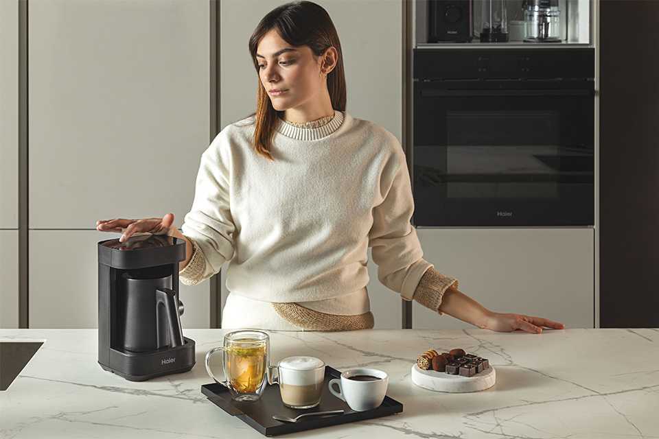 A woman using a Haier Multi Beverage coffee maker to prepare a cup of coffee.