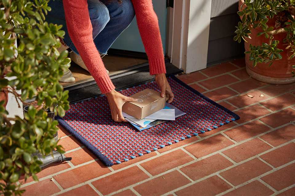 A person picking up HP Instant Ink delivery box at the doorstep.