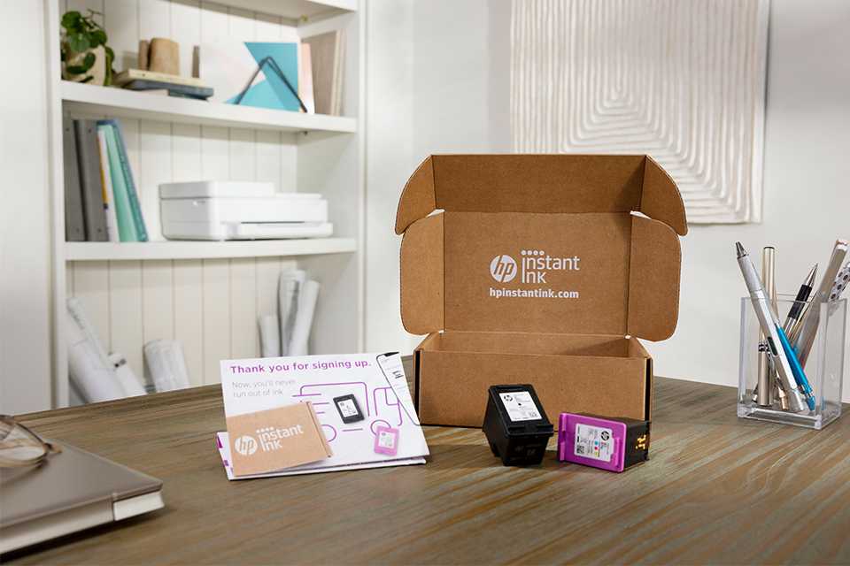HP Instant Ink delivery box with leaflet and two ink cartridges placed on top of a table.