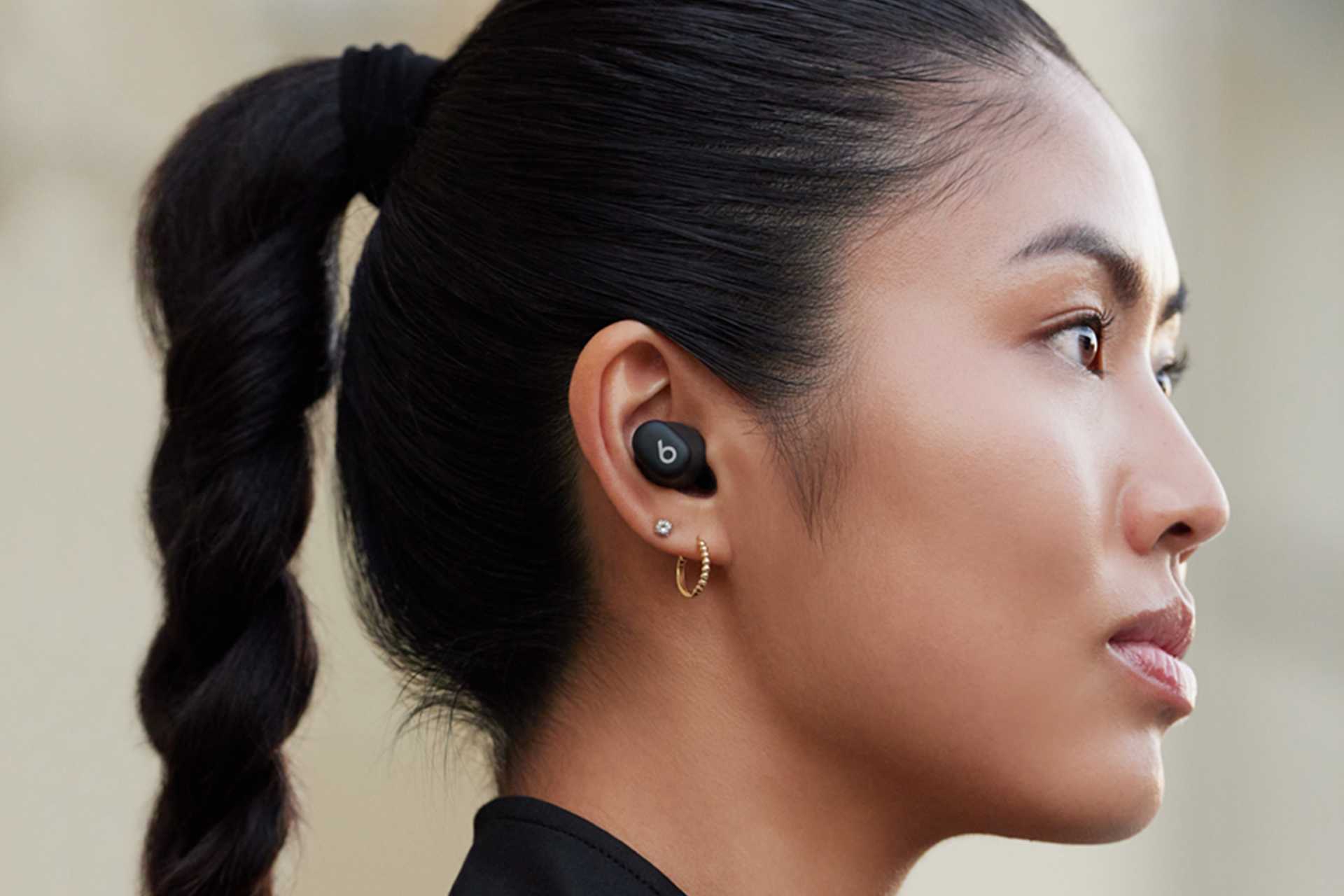 A woman wearing black Beats Studio earbuds.