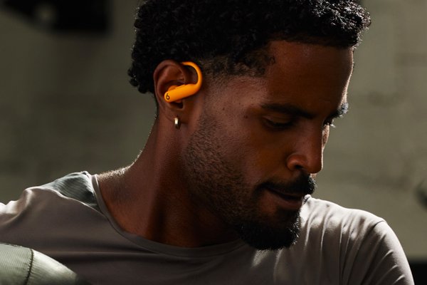 A man wearing Powerbeats Pro 2 in Electric Orange.