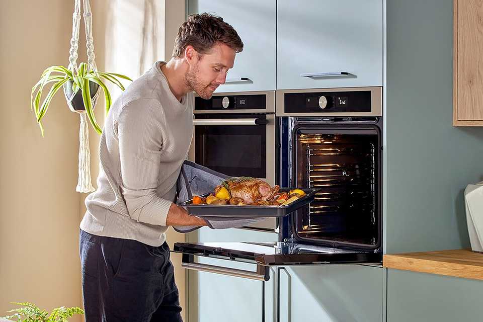A man using the Hotpoint MP4541XH 1000W built In combination microwave.