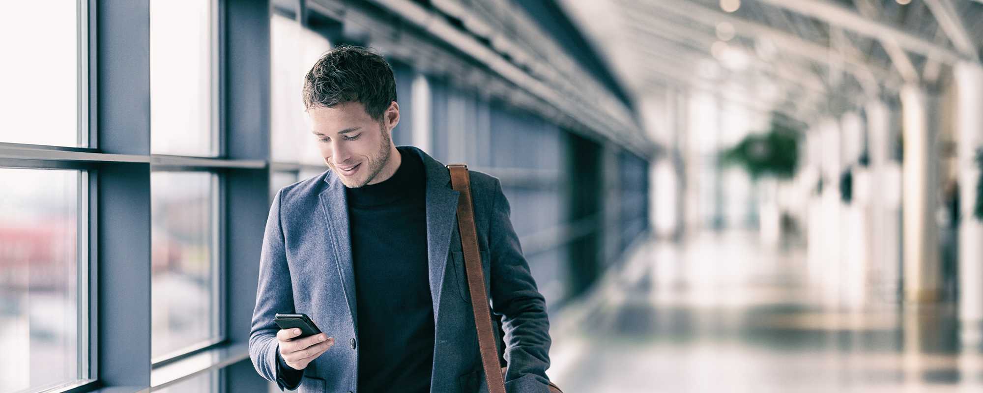 A man smiling at his mobile phone.