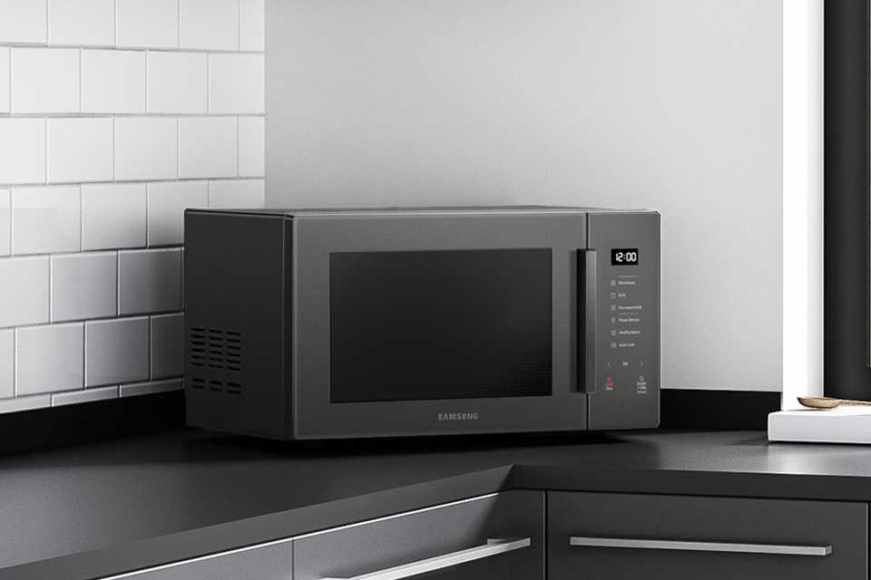 Samsung 800W 23L Standard Microwave in charcoal black placed on kitchen countertop.